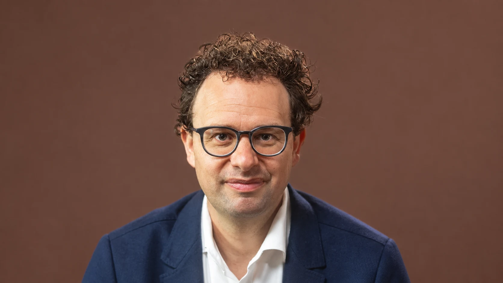 Portrait de Dario Amodei, cofondateur et directeur général d’Anthropic, sur un fond brun.